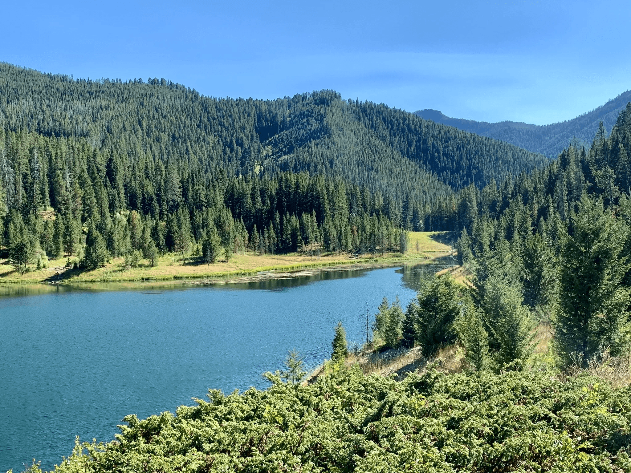 Upper view of Mystic Lake with blue water, forested hills, and mountain ridges
