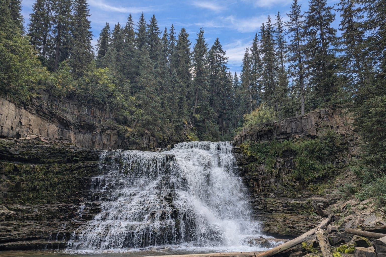 Ousel Falls cascading over tiered rock ledges surrounded by evergreen forest
