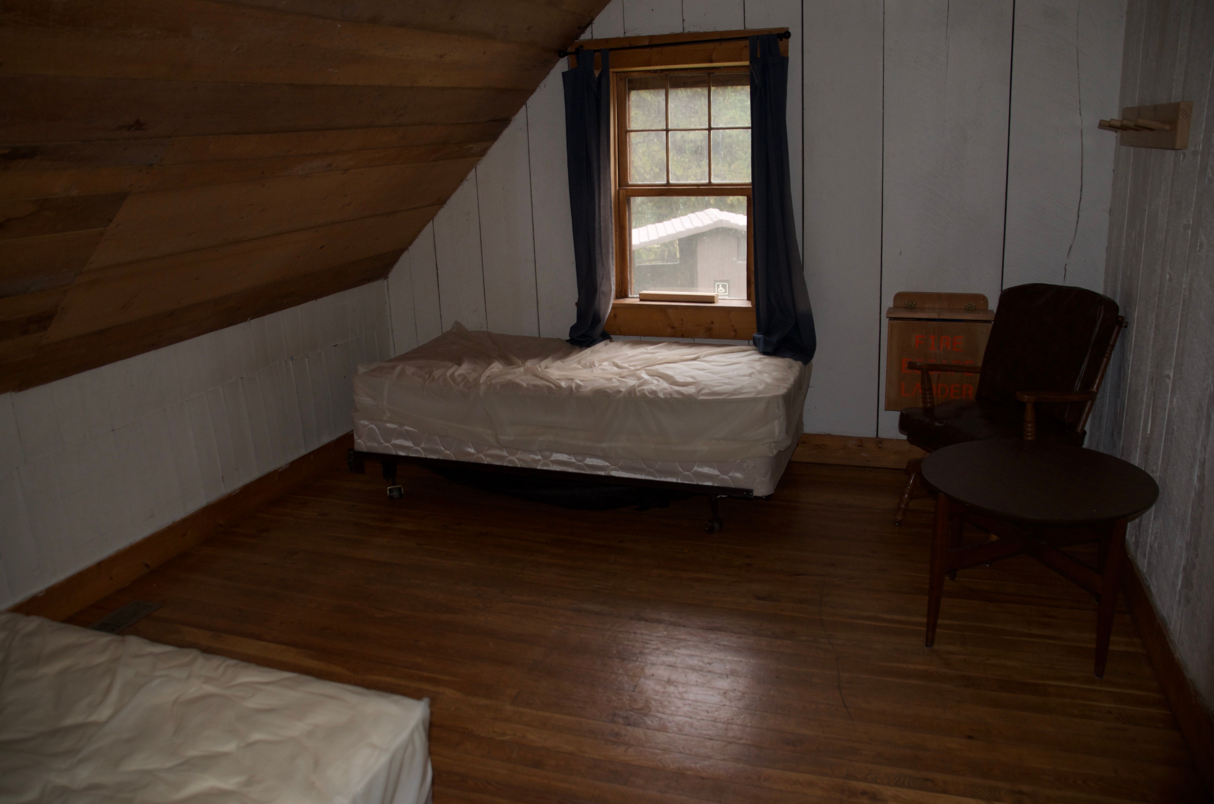 The back bedroom in the Wurtz Cabin loft with two twin beds and a window looking out at the property