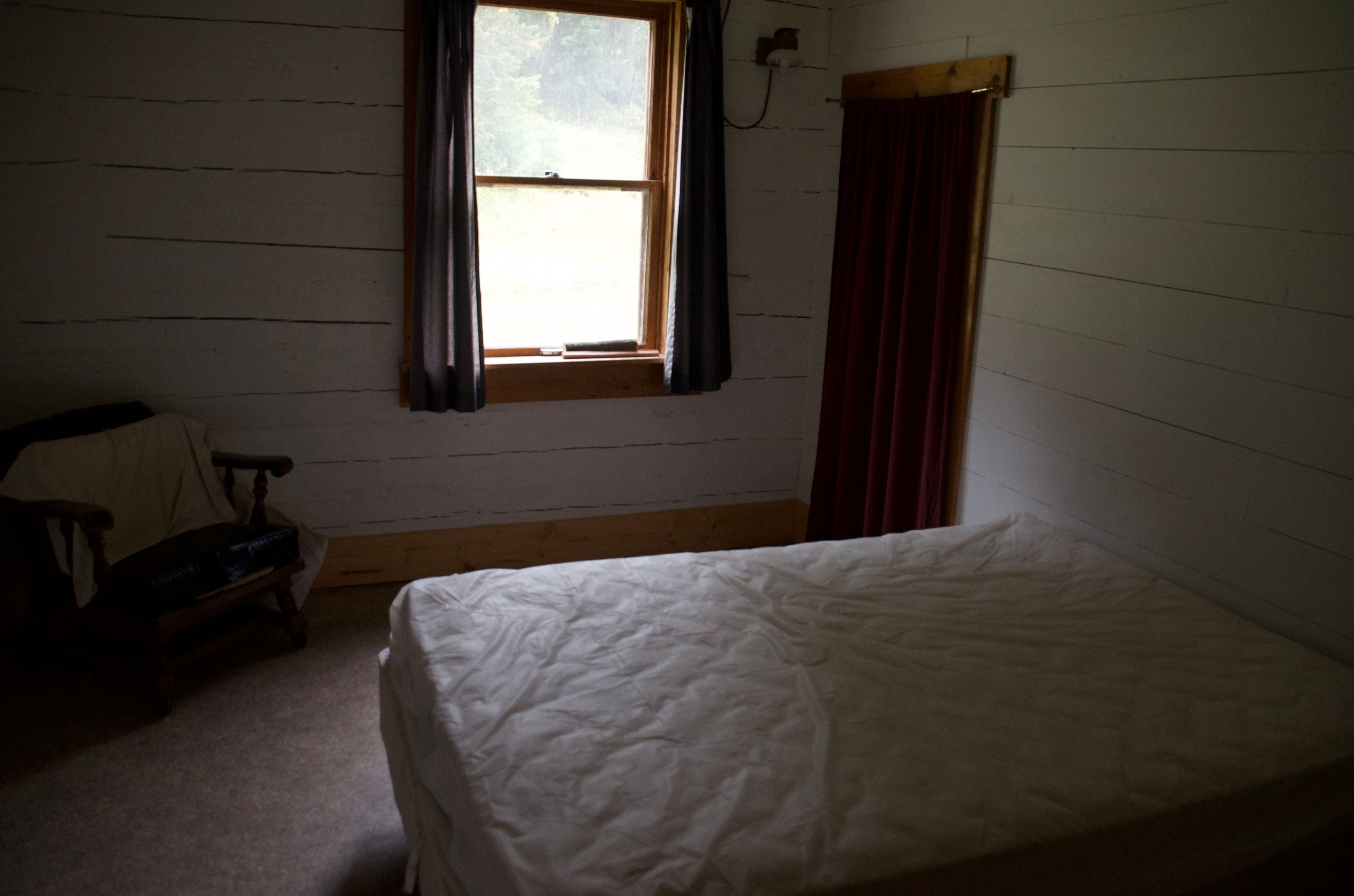 The main floor private bedroom at Wurtz Cabin with a double bed and window overlooking the yard