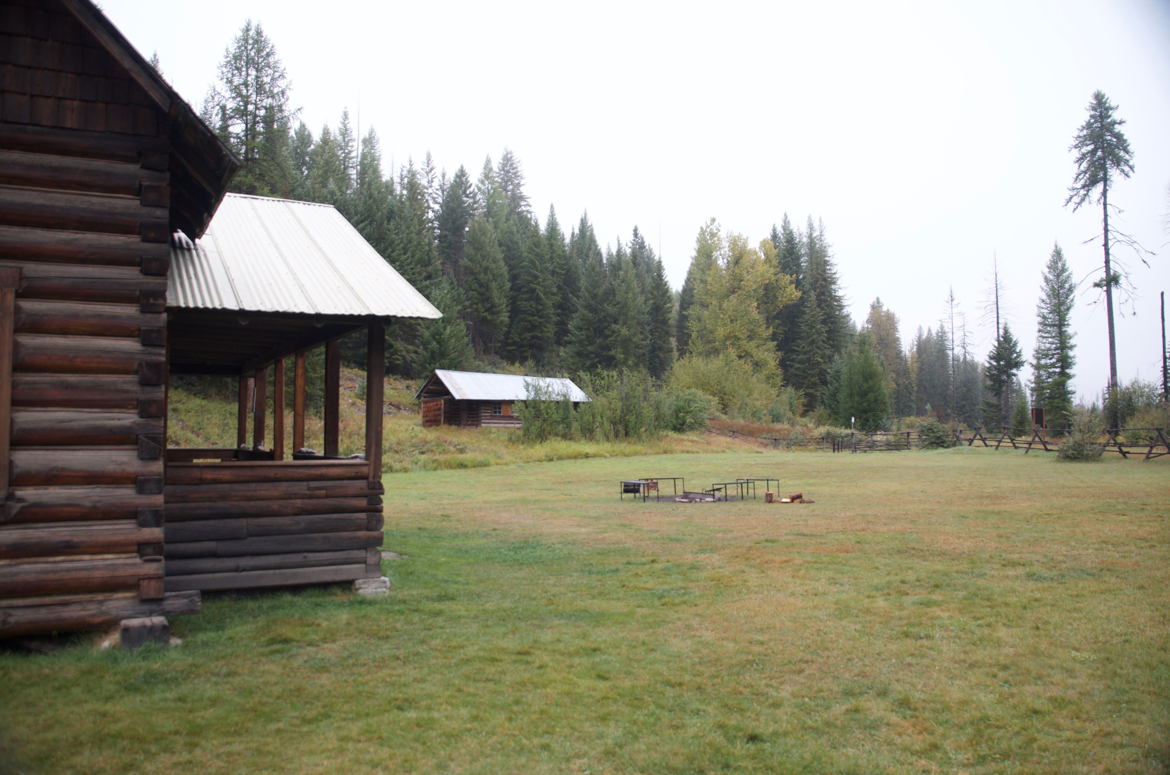 The grassy yard at Wurtz Cabin with a picnic table and the historic outbuilding visible in the background