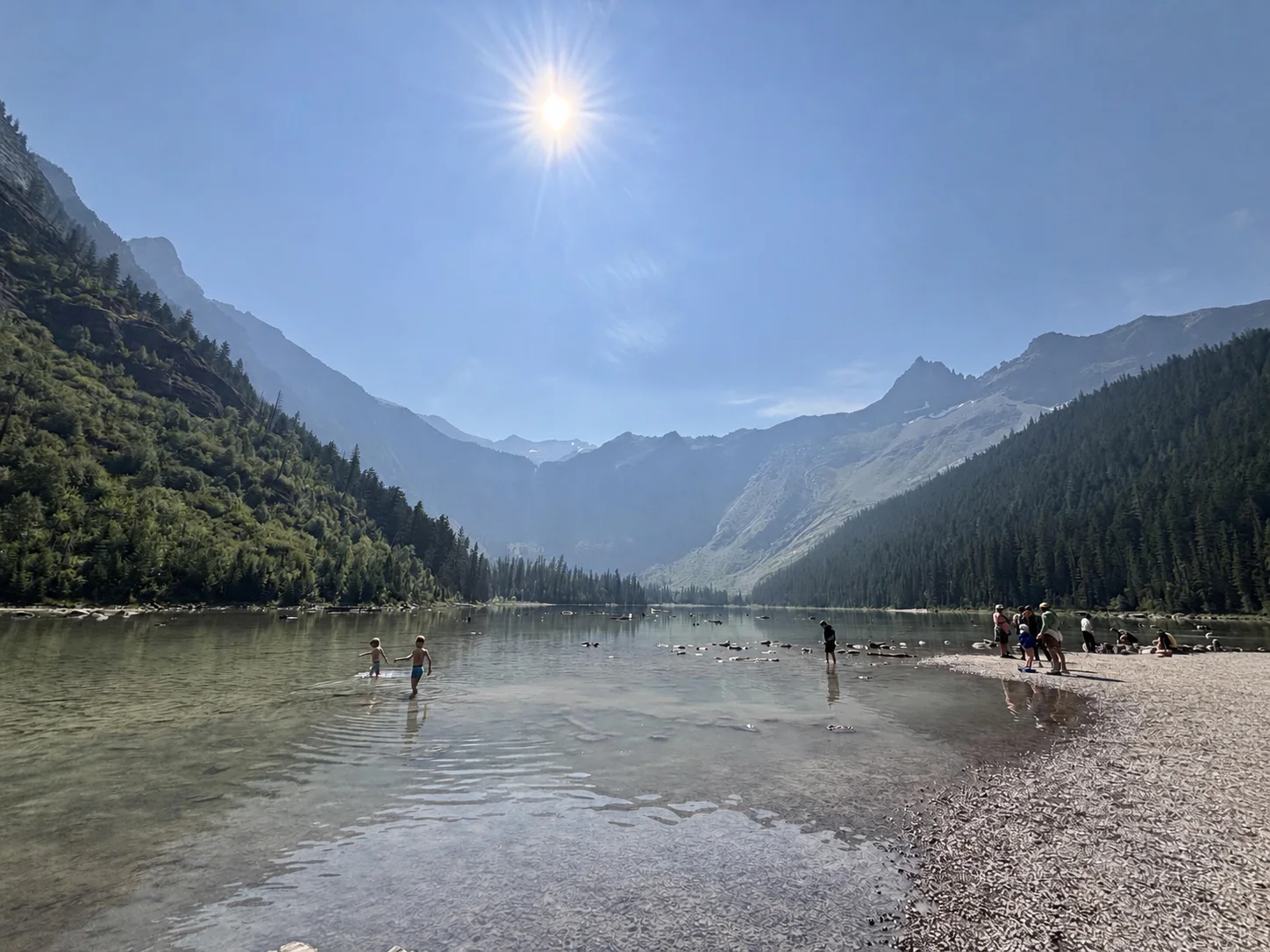 Avalanche Lake framed by steep Glacier National Park mountains beneath a bright summer sky
