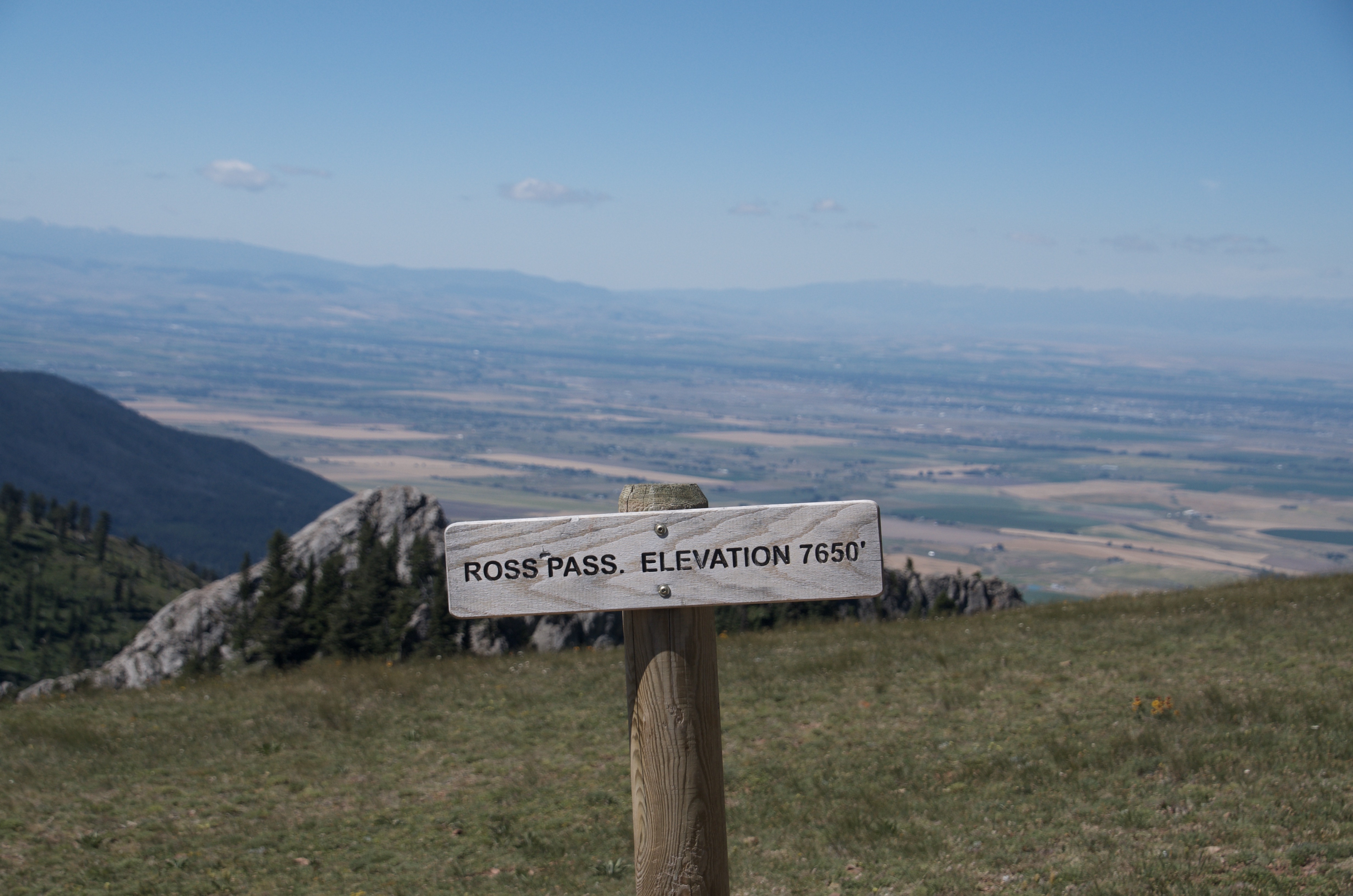Ross Pass elevation 7650 feet sign with hazy Gallatin Valley spread out far below