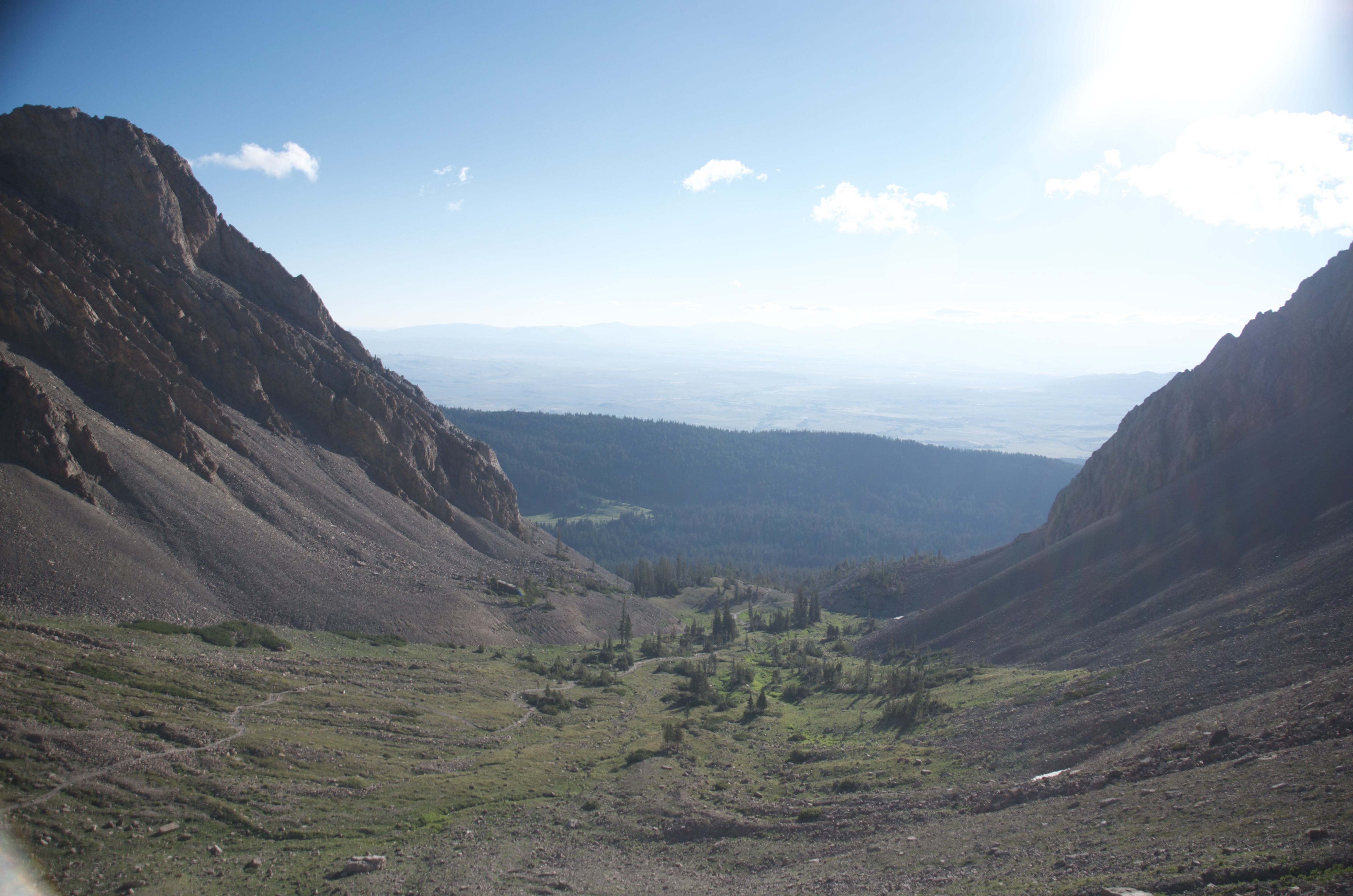 High couloir framing a view straight down to forested valley and flat Gallatin plains from the upper Bridger Ridge