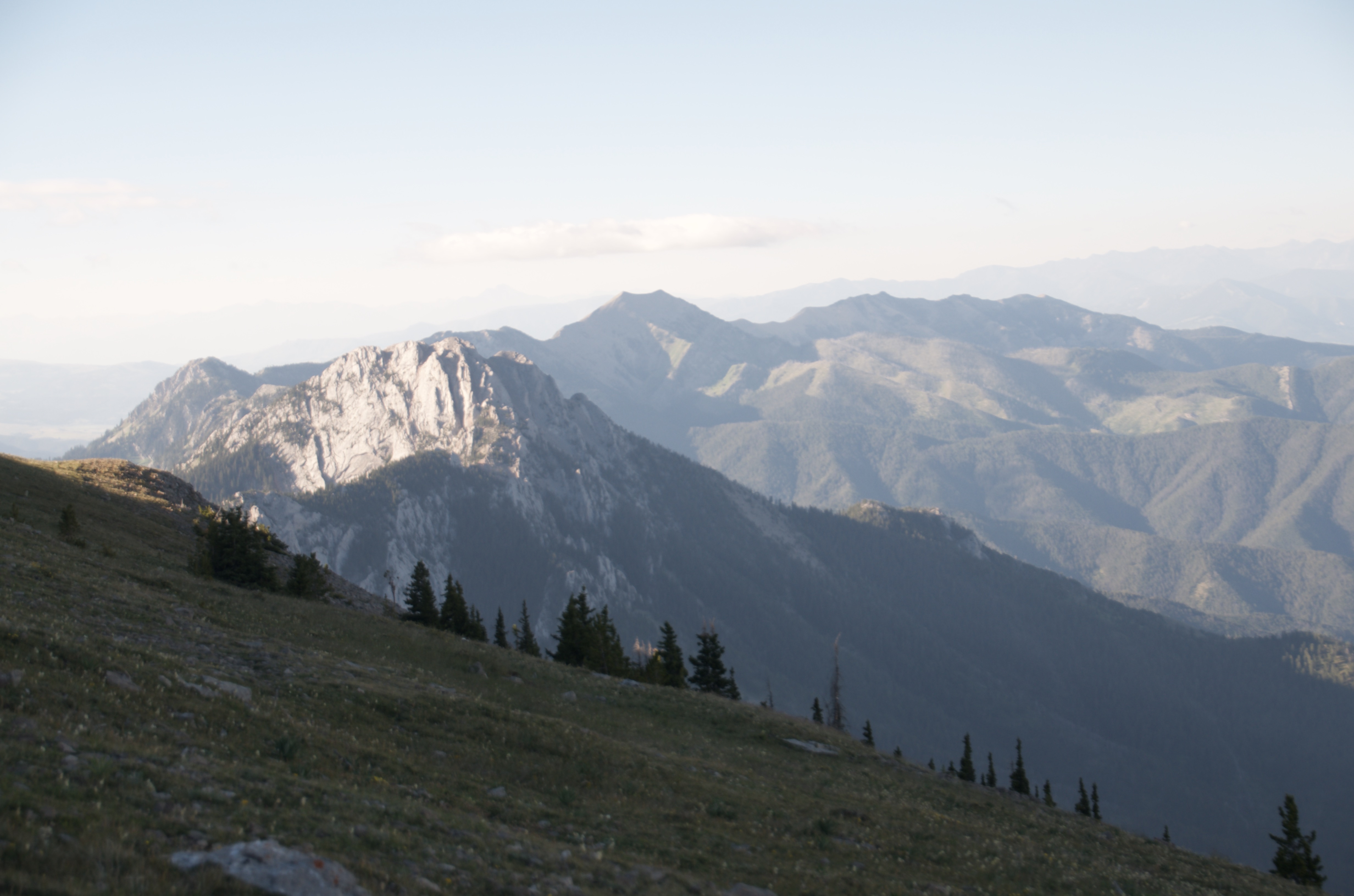 Early morning view south along Bridger Ridge with prominent limestone peak lit by low sun and layered ridges receding into haze