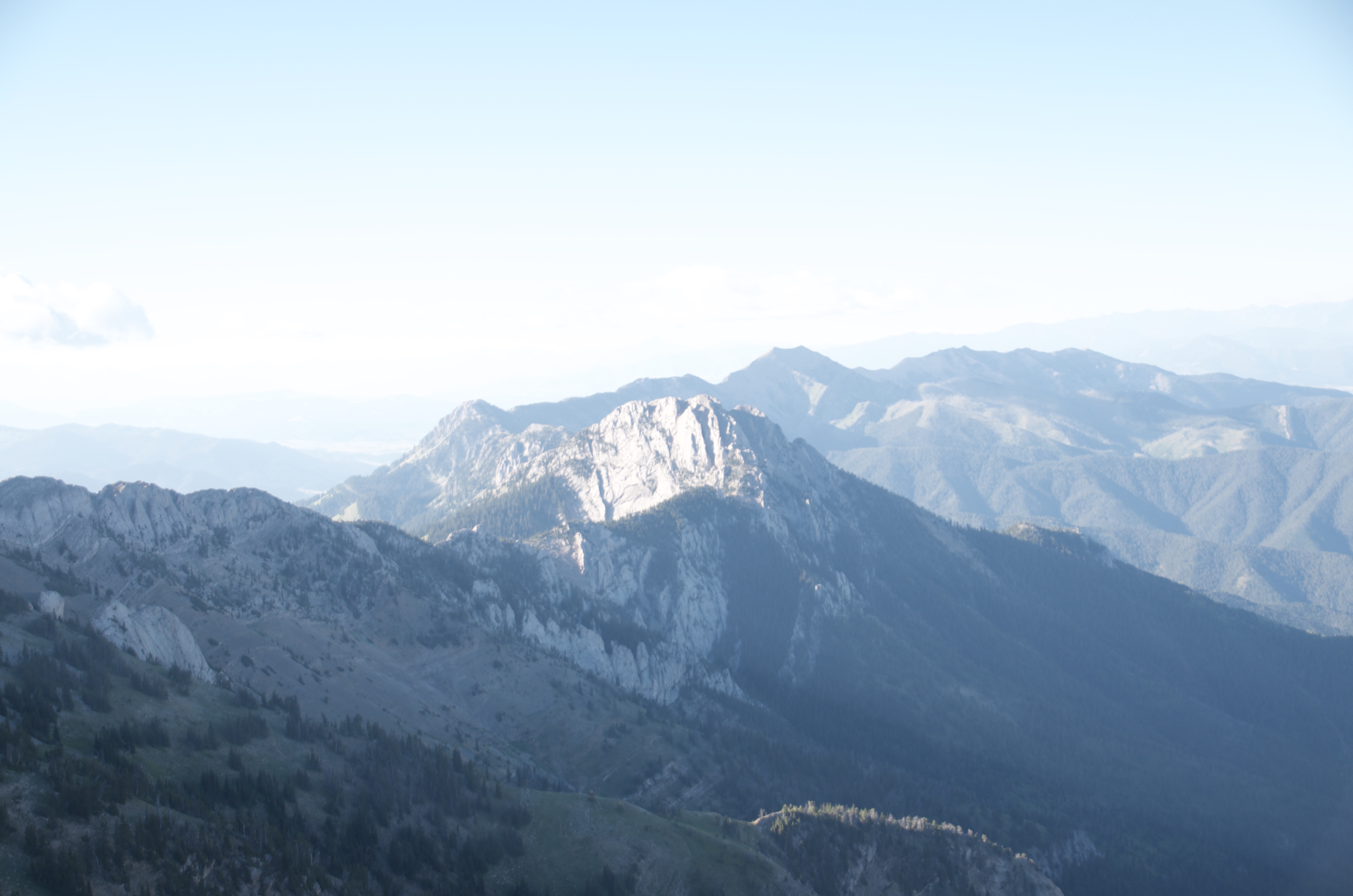Layered Bridger peaks in early morning haze viewed south along the ridge with forested slopes and valley below
