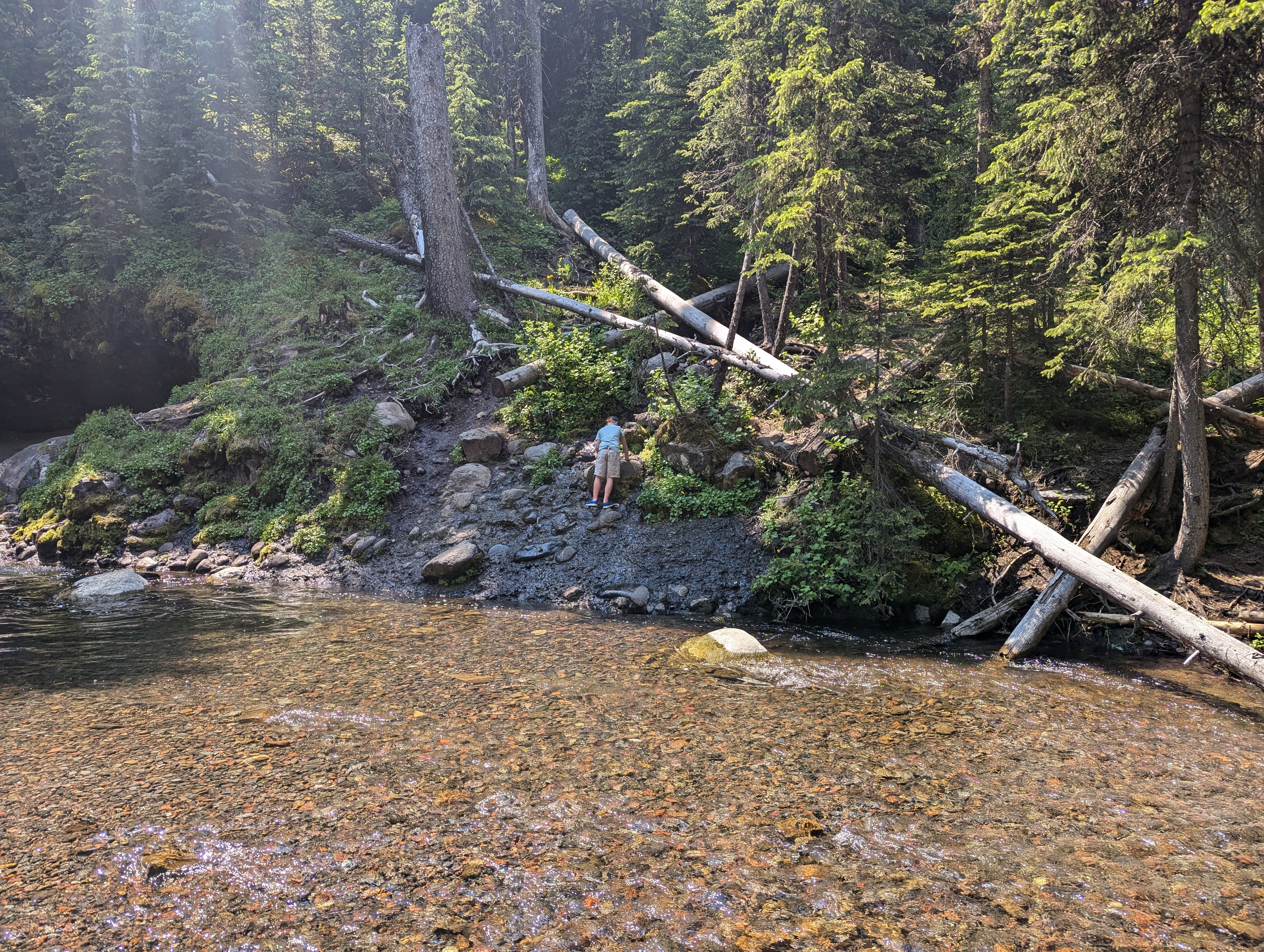 Hiker standing on rocks beside the clear shallow pool at the base of Grotto Falls