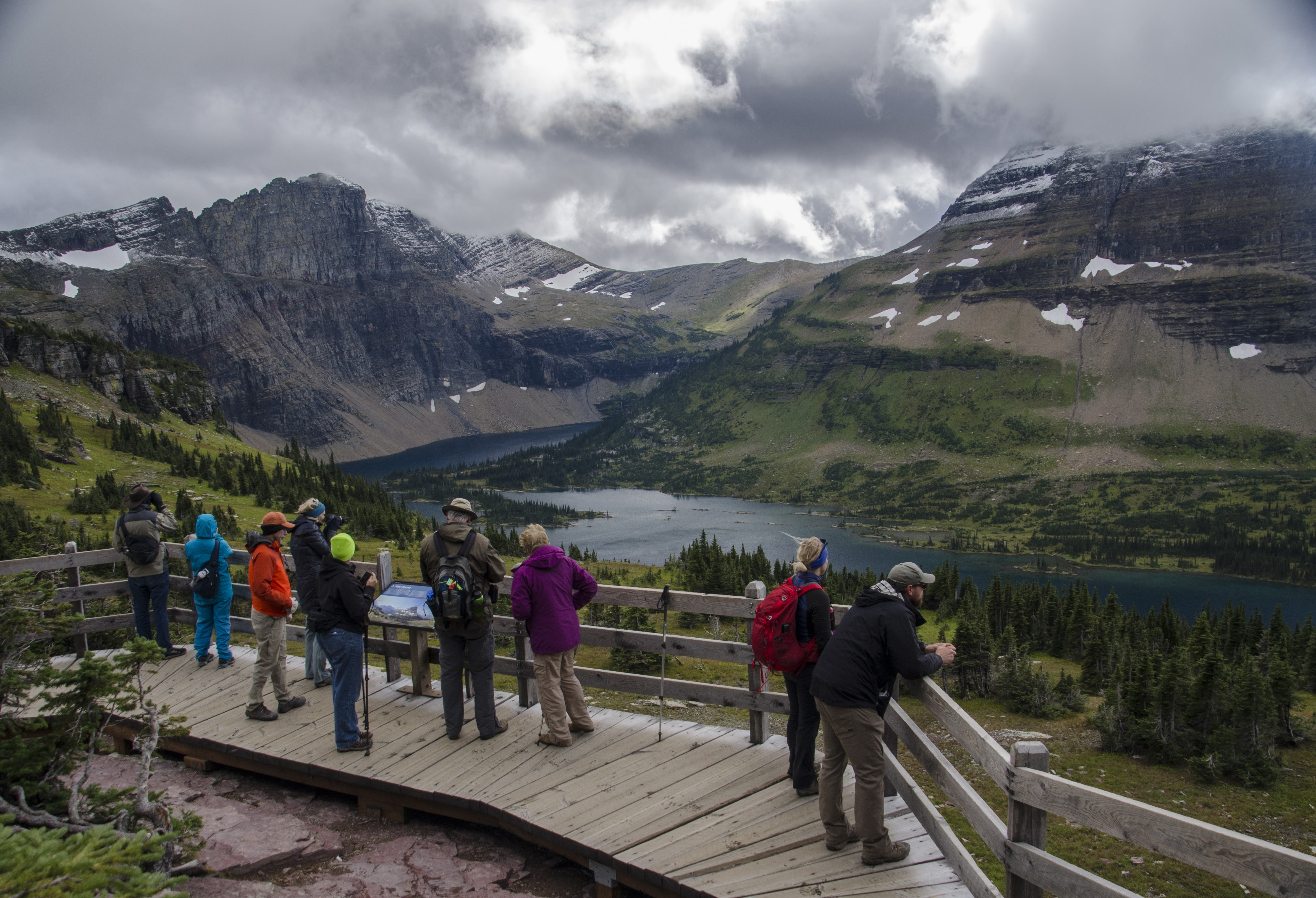 Crowded overlook deck packed with hikers viewing Hidden Lake and Bearhat Mountain