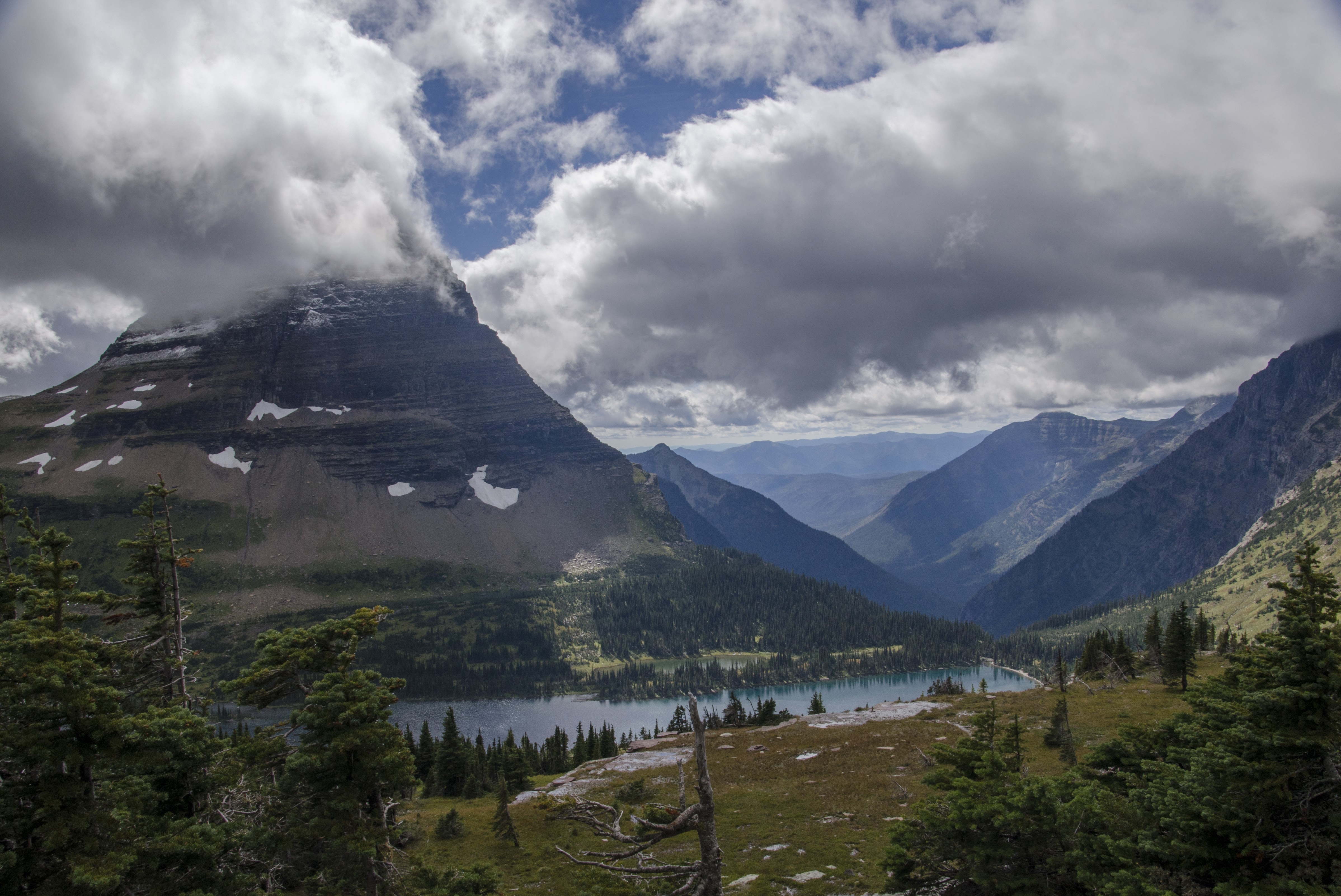 Bearhat Mountain rising above Hidden Lake with scattered evergreens and dramatic clouds