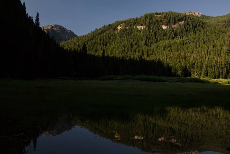 Blackmore Lake reflecting forested mountainside and Mount Blackmore peak
