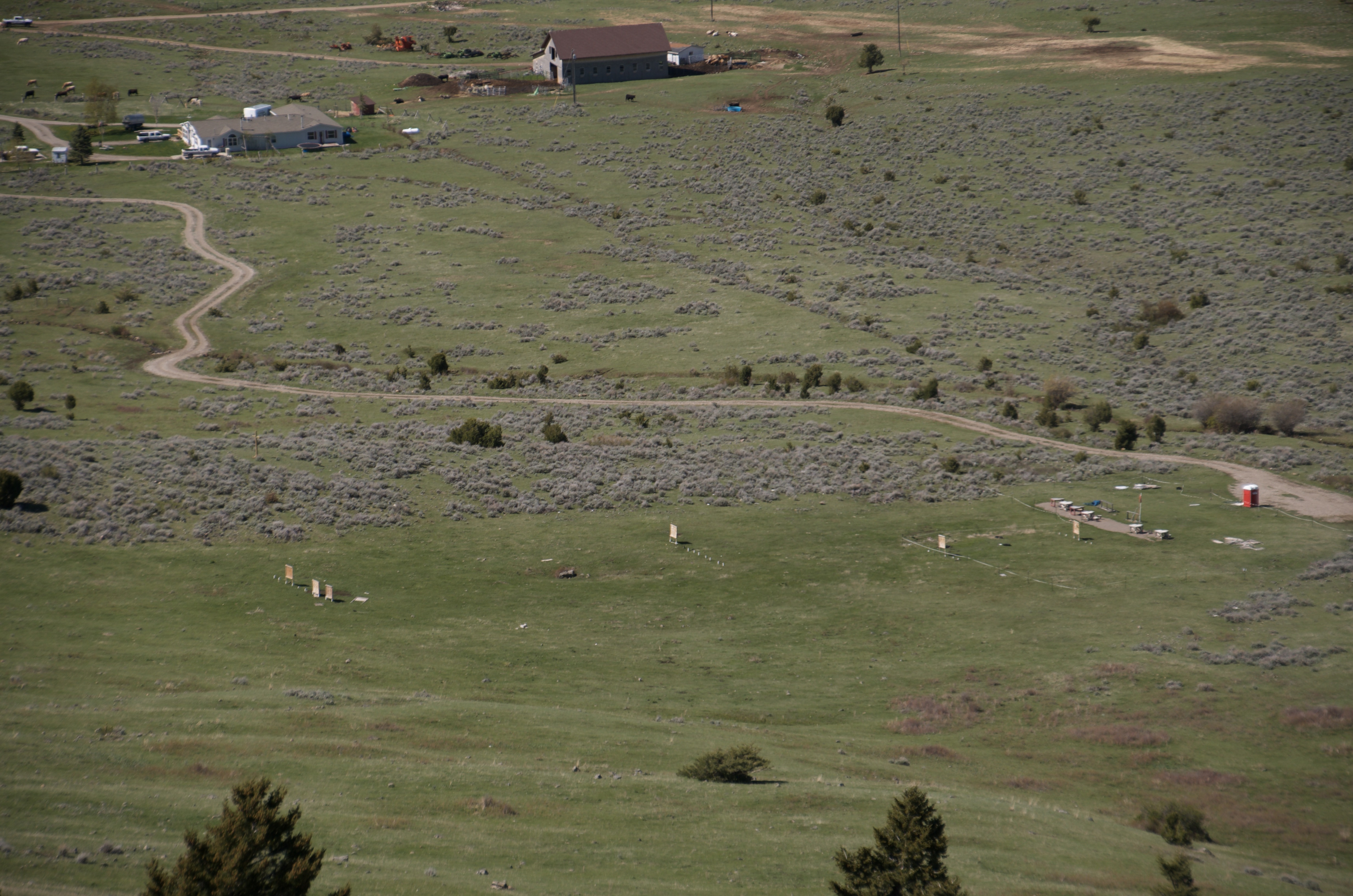 Looking down from above onto ranch buildings, winding gravel road, and open pastures in North Cottonwood drainage