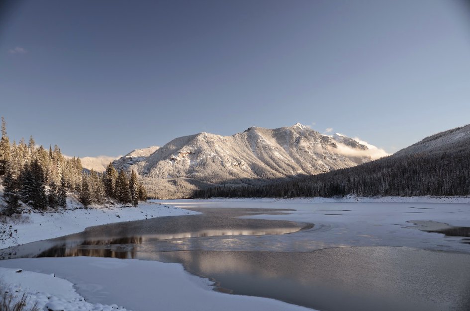 Partially frozen Hyalite Reservoir reflecting snow-covered peaks