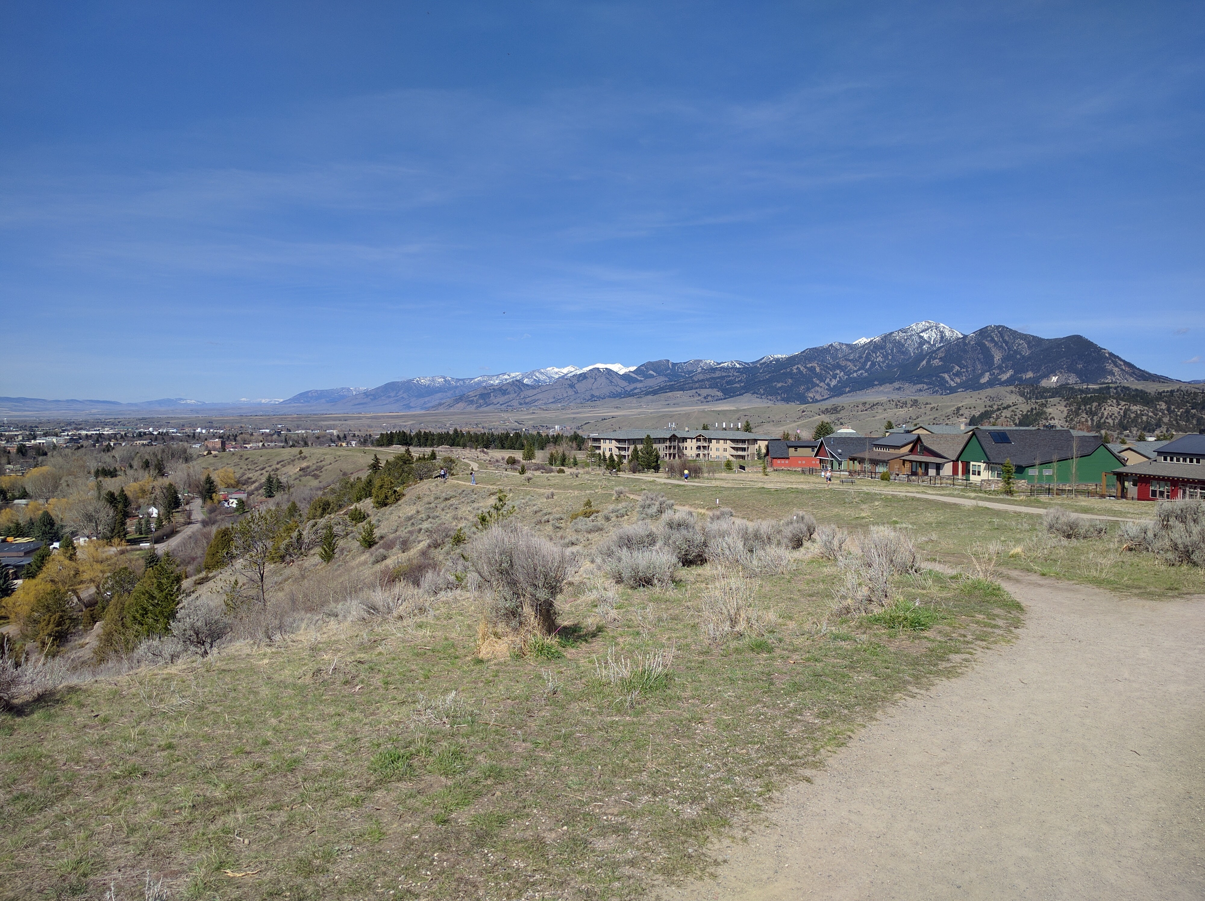 Gravel trail along the Peets Hill ridgeline with sagebrush hillside and snow-capped Gallatin Range in the distance