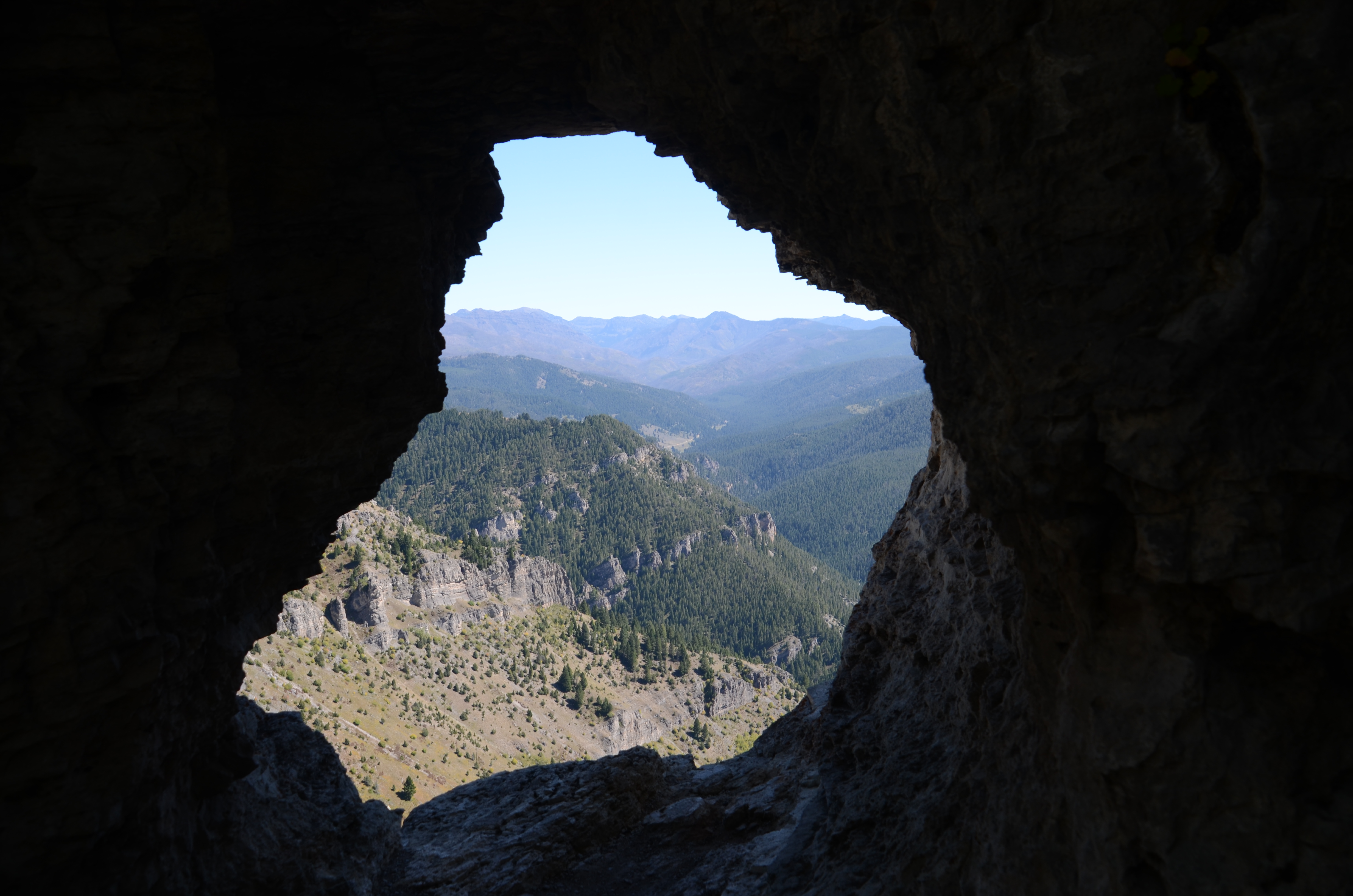 Looking out through the natural limestone arch of Storm Castle Peak at the forested canyon ridgelines below