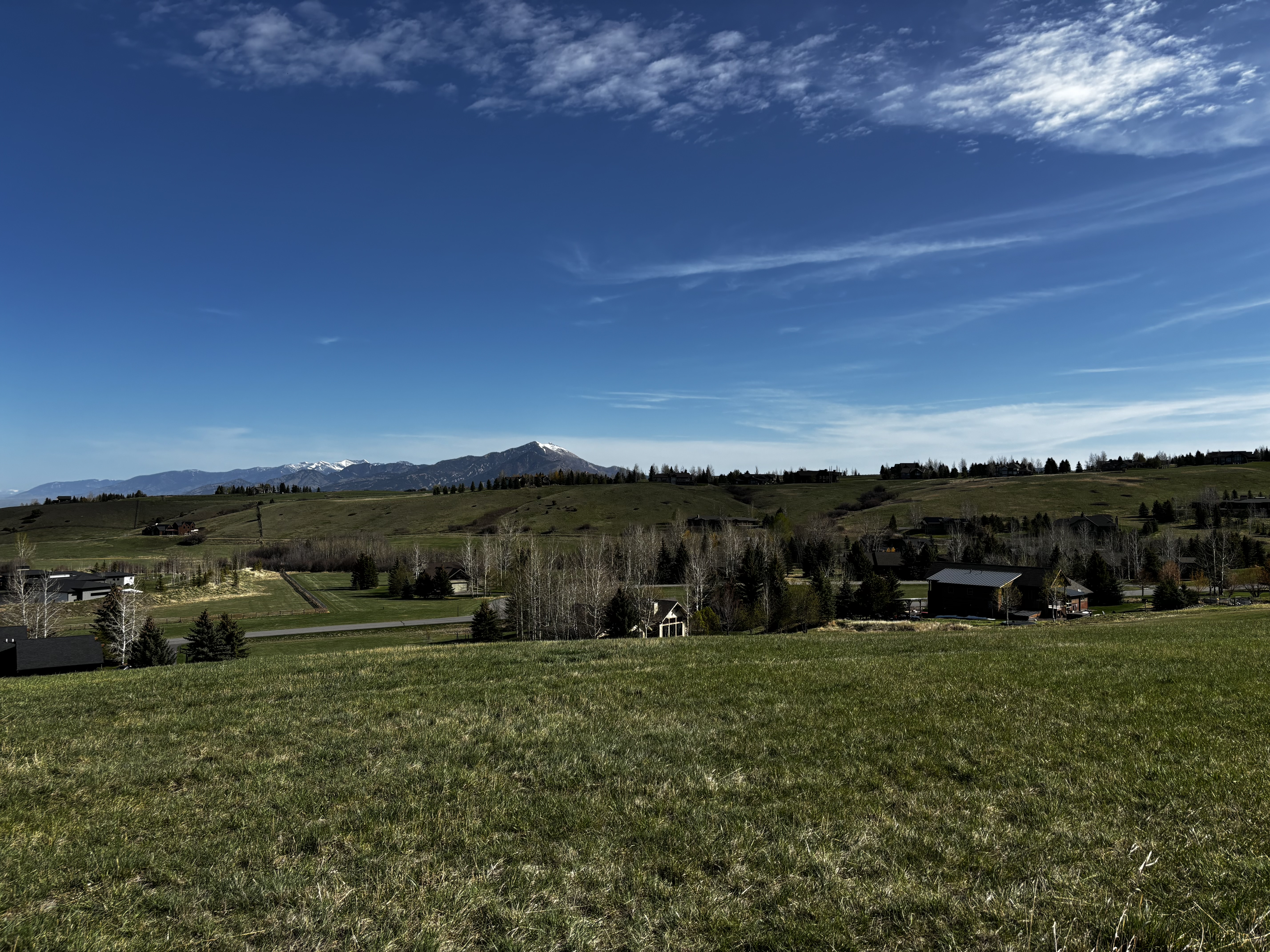 Wide pastoral view across the valley from the Triple Tree Trail with ranch houses, trees, and snow-capped mountains in the distance