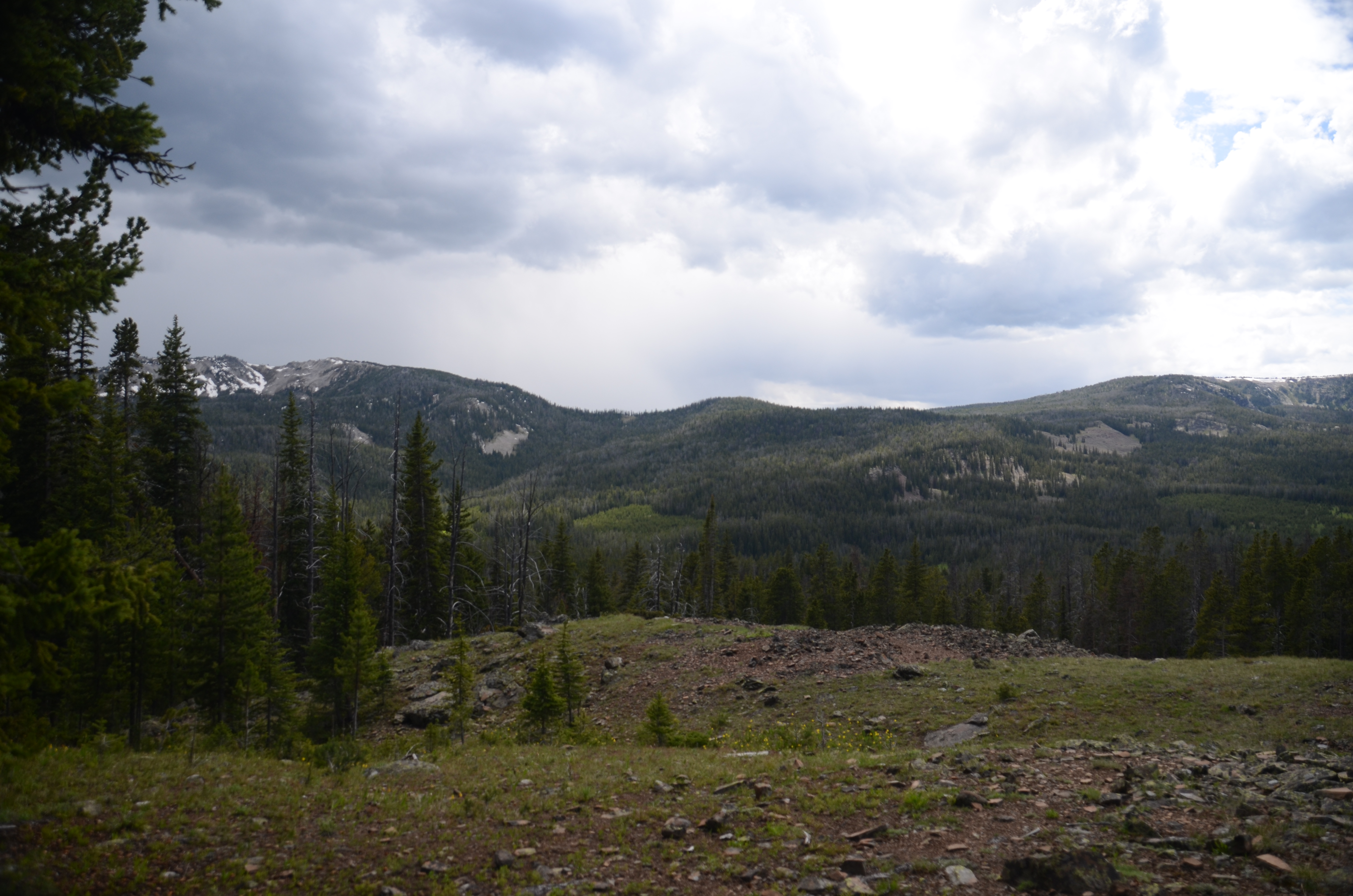 Rocky open terrain on the upper Windy Pass trail with panoramic mountain views and building afternoon clouds