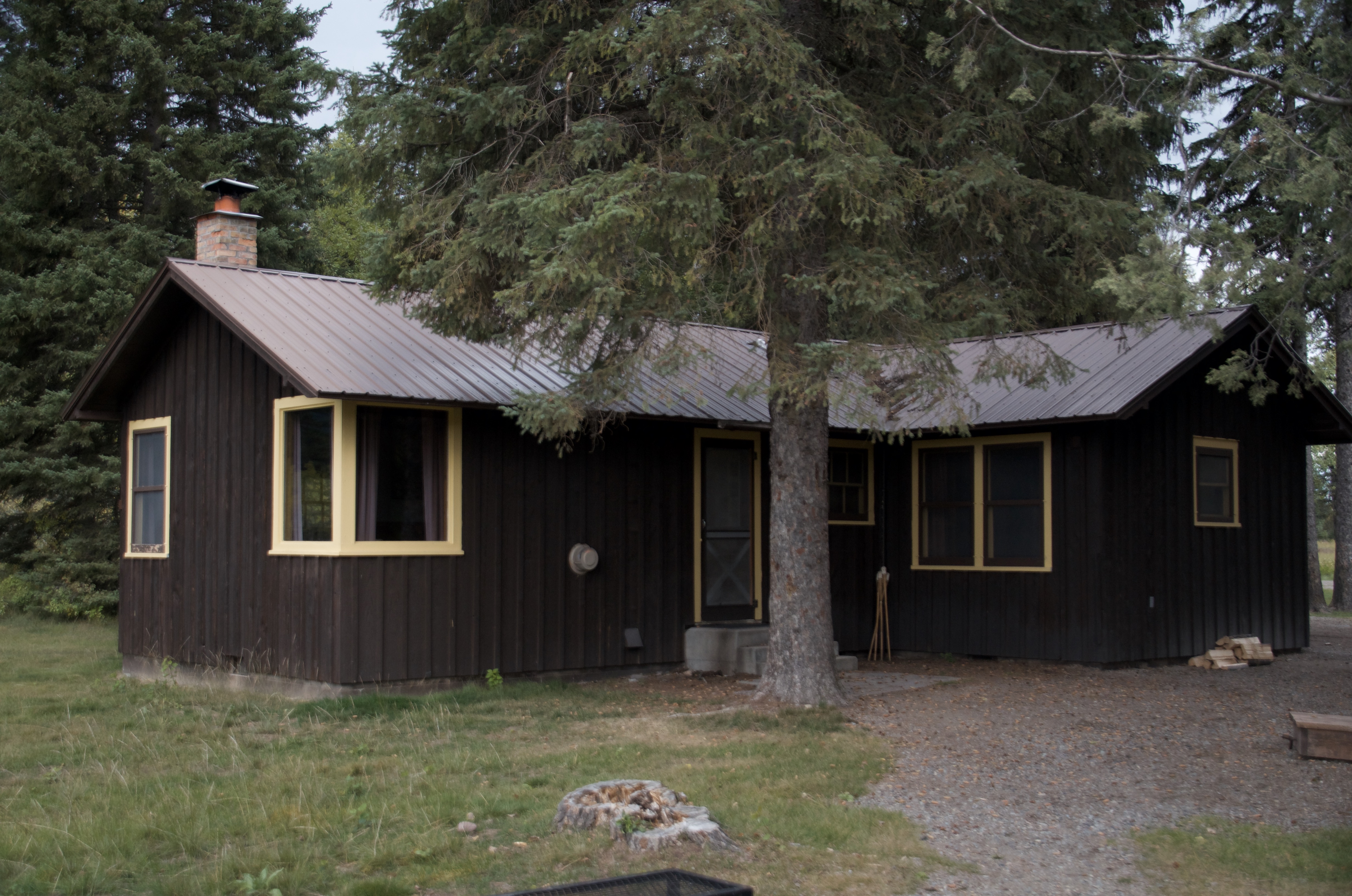 Ben Rover Cabin exterior, a dark wood Forest Service cabin with yellow trim near Polebridge, Montana