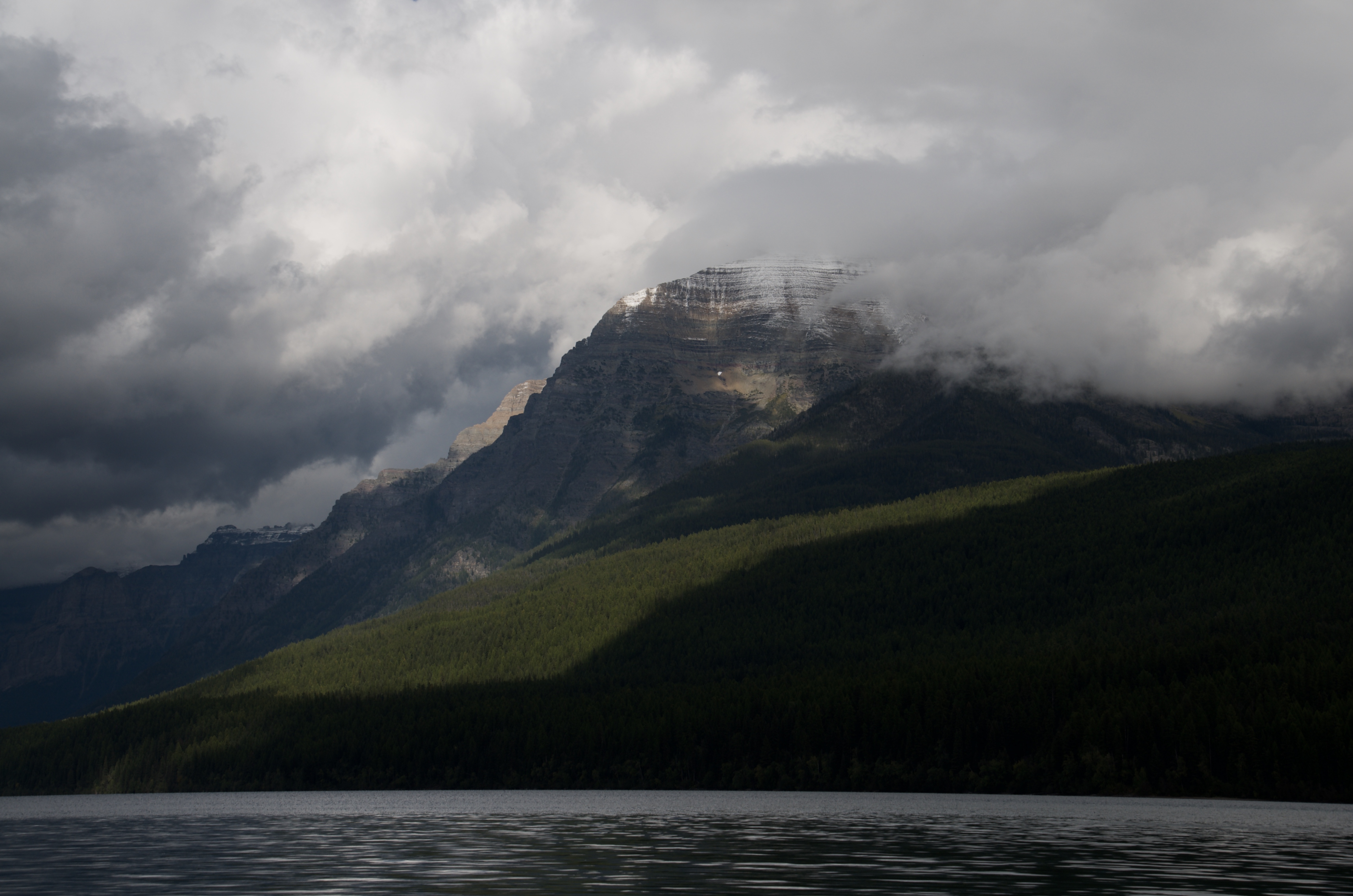 Dramatic Glacier National Park peak emerging from storm clouds above Bowman Lake